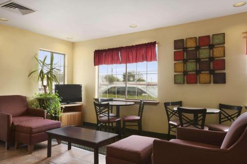 a waiting room with chairs and a table and a tv at Howard Johnson by Wyndham Grand Prairie Near Lone Star Park in Grand Prairie