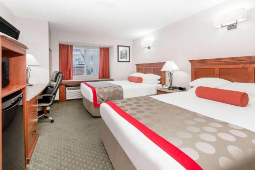 a hotel room with two beds and a flat screen tv at Ramada by Wyndham Frisco in Frisco