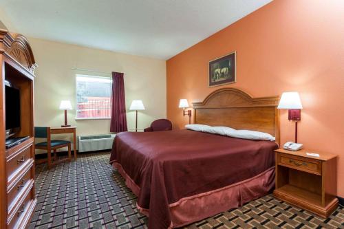 Habitación de hotel con cama y TV en Howard Johnson by Wyndham Airport en Louisville