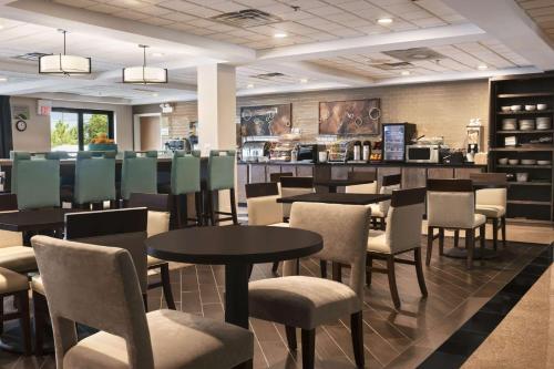 a restaurant with tables and chairs and a counter at Wingate by Wyndham Chicago Schaumburg in Schaumburg