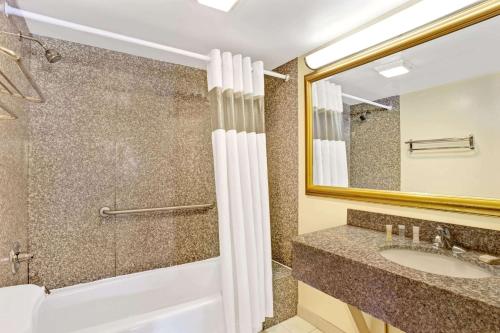 y baño con ducha, lavabo y espejo. en Howard Johnson by Wyndham Pikesville, en Pikesville