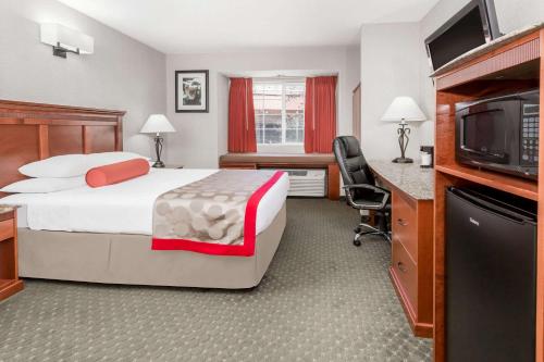 a hotel room with a bed and a flat screen tv at Ramada by Wyndham Frisco in Frisco