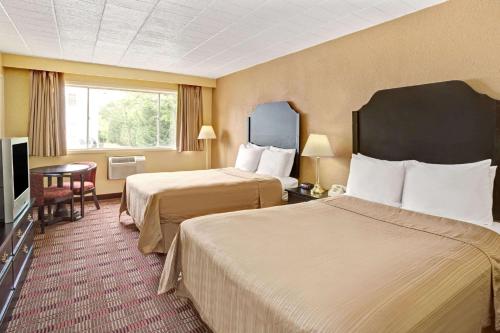 a hotel room with two beds and a television at Howard Johnson by Wyndham Pikesville in Pikesville