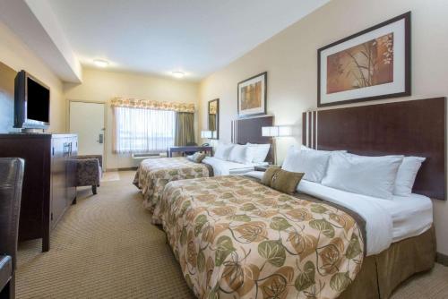 a hotel room with two beds and a television at Ramada by Wyndham Wainwright in Wainwright