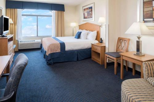 a hotel room with a bed and a couch at Wingate by Wyndham Spokane Airport in Spokane