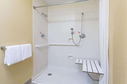 a bathroom with a shower with a bench in it at Microtel Inn & Suites by Wyndham Hillsborough in Hillsborough