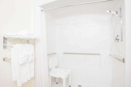 a white bathroom with a shower and white towels at Microtel Inn & Suites by Wyndham Plattsburgh in Plattsburgh