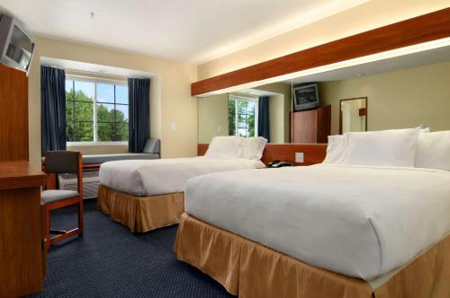 a hotel room with two beds and a desk at Microtel Inn & Suites Huntsville in Huntsville