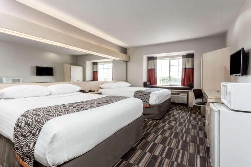 a hotel room with two beds and a flat screen tv at Microtel Inn & Suites Modesto in Ceres