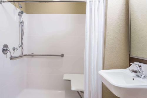 a bathroom with a sink and a white shower curtain at Microtel Inn & Suites by Wyndham Jacksonville Airport in Jacksonville