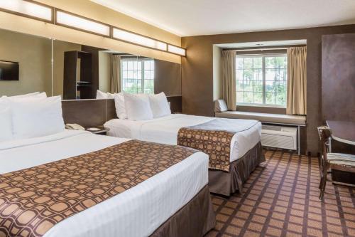 a hotel room with two beds and a window at Microtel Inn & Suites by Wyndham Jacksonville Airport in Jacksonville