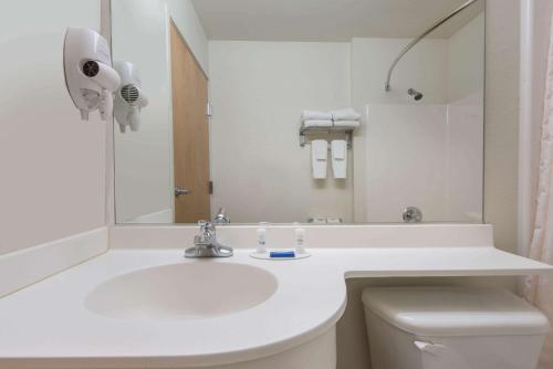 a white bathroom with a sink and a mirror at Microtel Inn & Suites by Wyndham Altus in Altus