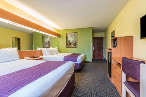 a hotel room with two beds and a flat screen tv at Microtel Inn & Suites by Wyndham Auburn in Auburn