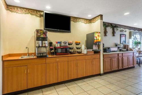 a kitchen with wooden cabinets and a flat screen tv at Microtel Inn & Suites by Wyndham Auburn in Auburn