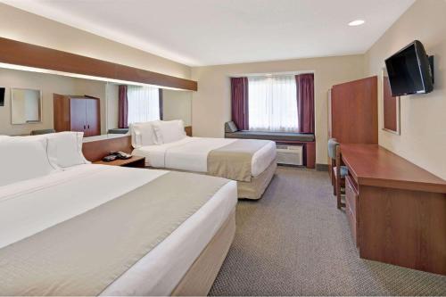 a hotel room with two beds and a flat screen tv at Microtel Inn & Suites by Wyndham Jasper in Jasper
