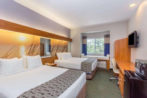 a hotel room with two beds and a desk at Microtel Inn & Suites by Wyndham Port Charlotte Punta Gorda in Port Charlotte