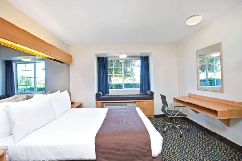 a hotel room with a large bed and a desk at Microtel Inn & Suites, Morgan Hill in Morgan Hill