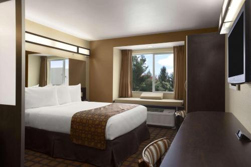 オデッサにあるMicrotel Inn & Suites by Wyndham Odessa TXのベッドと窓が備わるホテルルーム