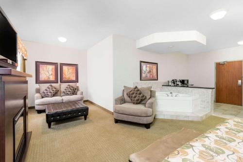 a living room with a bed and a couch and a tv at Ramada by Wyndham Olds in Olds