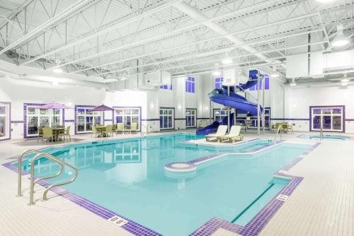 a large swimming pool with a slide in a building at Ramada by Wyndham Olds in Olds