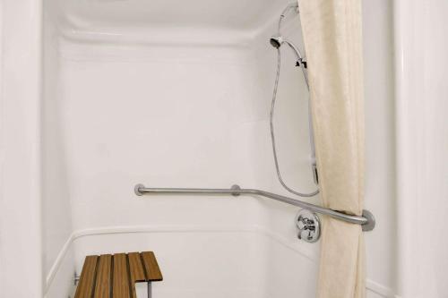 baño con cortina de ducha y banco de madera en Howard Johnson by Wyndham Tifton GA I-75, en Tifton