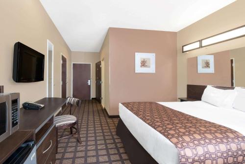 a hotel room with a bed and a flat screen tv at Microtel Inn & Suites in Sidney