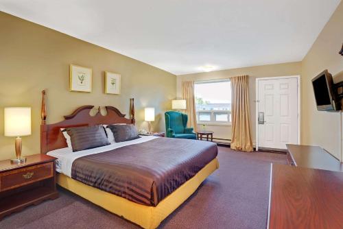 ein Hotelzimmer mit einem großen Bett und einem TV in der Unterkunft Howard Johnson by Wyndham Lindsay in Lindsay