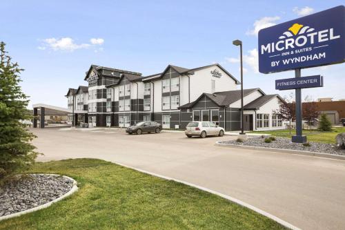 a hotel with cars parked in a parking lot at Microtel Inn & Suites by Wyndham Blackfalds in Blackfalds