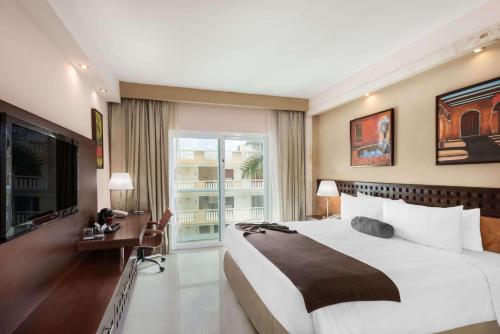 Wyndham Merida في ميريدا: غرفة نوم كبيرة مع سرير كبير وشرفة