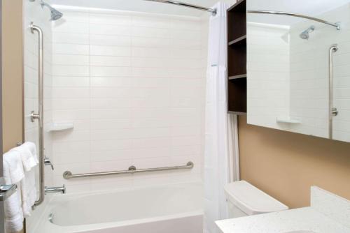 a bathroom with a shower and a toilet and a sink at Microtel Inn & Suites by Wyndham Red Deer in Red Deer