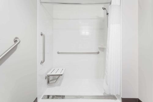baño blanco con ducha y banco en Microtel Inn & Suites by Wyndham Kirkland Lake, en Kirkland Lake