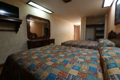 a hotel room with two beds and a mirror at Hotel Isabel I in Oaxaca City