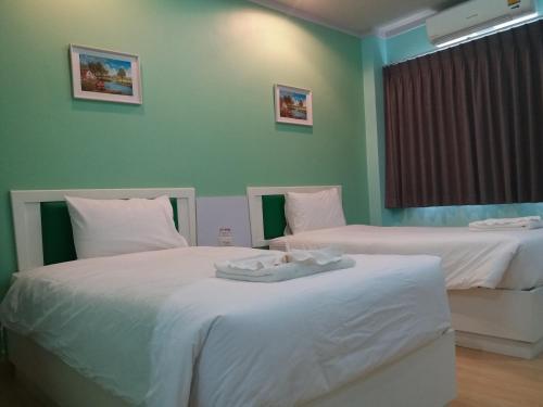 two beds in a room with green walls at Kradang Nga Boutique Inn in Khun Han