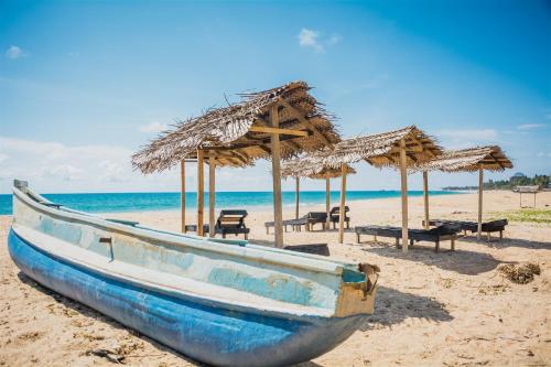 a blue boat sitting on a beach with umbrellas at Sailors' Bay in Hikkaduwa