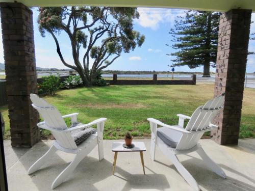two white chairs and a table on a porch at Pohutukawa Bach in Whangarei