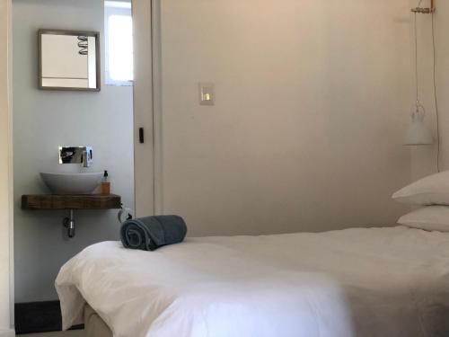 1 dormitorio con cama blanca y lavamanos en 41 on Serruria en Stellenbosch