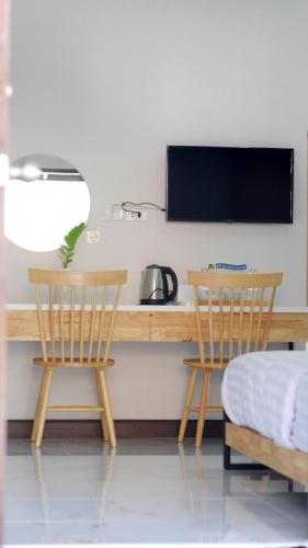 2 Stühle und ein Schreibtisch mit einem TV an der Wand in der Unterkunft Kudao Rent Room in Chiang Mai