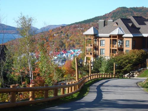 uma estrada em frente a uma casa com uma cerca em L'Équinoxe Rendez-Vous Mont-Tremblant em Mont-Tremblant