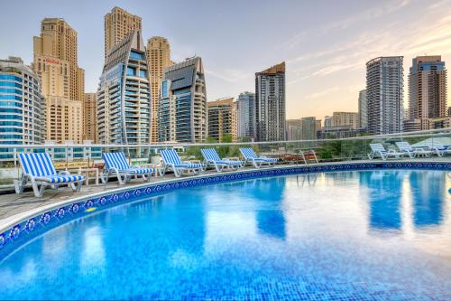 a swimming pool with chairs and a city skyline at Pearl Marina Hotel Apartments in Dubai