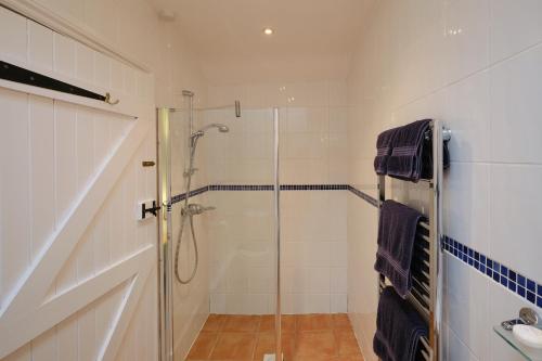 a bathroom with a shower with a glass door at Cobblestone Cottage in Penzance