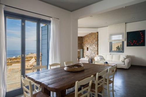 a living room with a wooden table and chairs at Luxury Cycladic Villa-Enjoy Infinity Pool Sunsets in Koundouros
