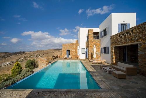 a villa with a swimming pool in front of a building at Luxury Cycladic Villa-Enjoy Infinity Pool Sunsets in Koundouros
