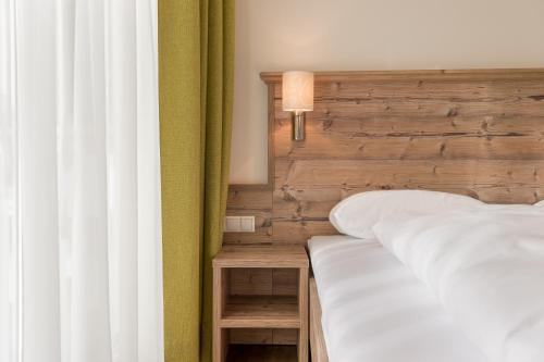 a bedroom with a white bed with a wooden headboard at A Casa Saphir Appartement-Hotel in Sölden