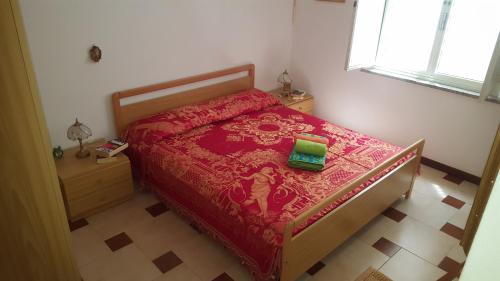 a bedroom with a bed with a red comforter and a green book at Appartamento Bouganville in Magomadas