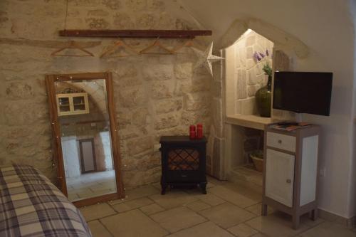 Habitación con TV y pared de piedra. en Dimora Levante, en Ostuni