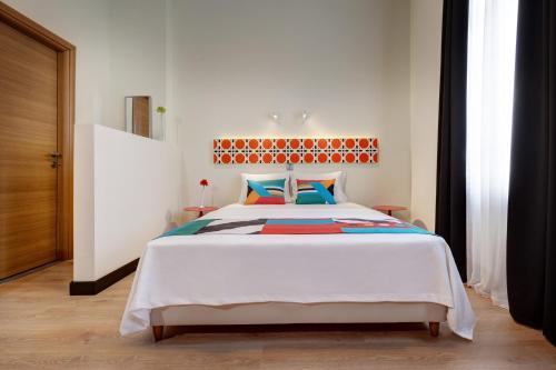 ein Schlafzimmer mit einem großen weißen Bett mit bunten Kissen in der Unterkunft Colors Ladadika Thessaloniki in Thessaloniki