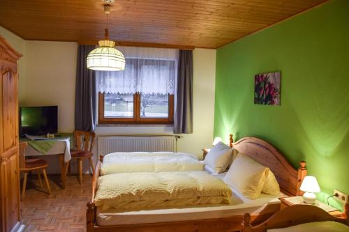 a bedroom with a green wall with a bed and a table at Gasthof Gruber in Wald am Schoberpaß