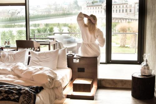 a woman in a robe looking out of a window at Castel Mimi Wine Resort in Bulboaca