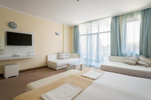 a hotel room with two beds and a large window at Hotel Perla Beach Club - All Inclusive in Primorsko
