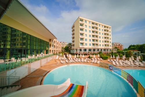 a hotel swimming pool with chairs and a building at Hotel Perla Beach Club - All Inclusive in Primorsko